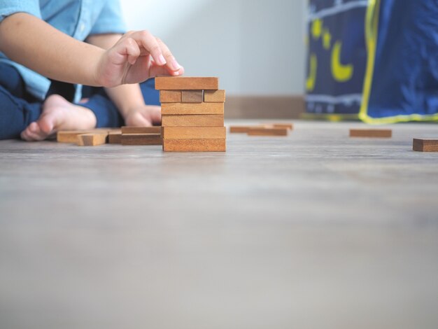 Piccolo bambino che gioca con blocchi di legno sul pavimento