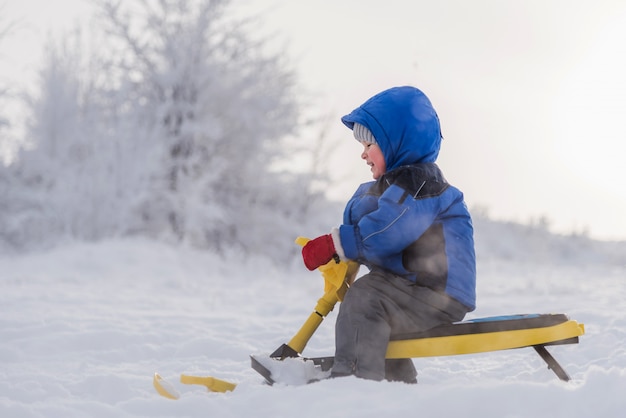 Piccolo bambino che guida un motorino di neve in inverno