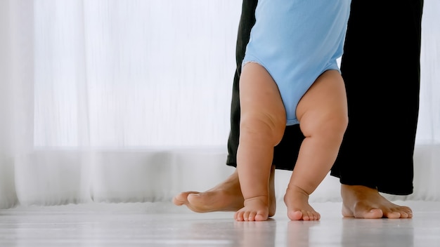 Piccolo bambino che impara a camminare con il supporto e la cura della madre.