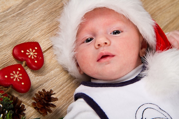 Piccolo bambino con il cappello di natale su legno con la decorazione di natale