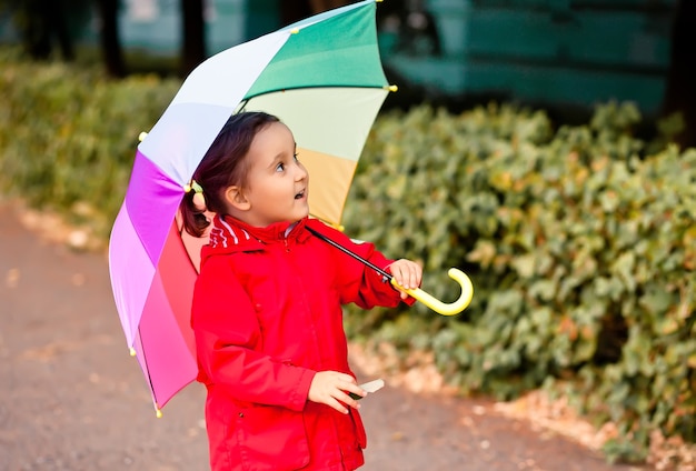 Piccolo bambino con ombrello arcobaleno multicolore all'aperto.