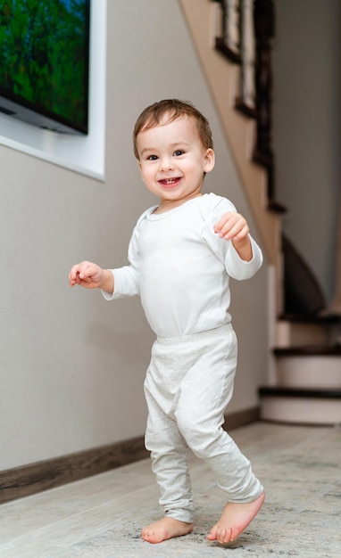 Piccolo bambino divertente che gioca sul pavimento Ragazzo carino che gioca nella stanza