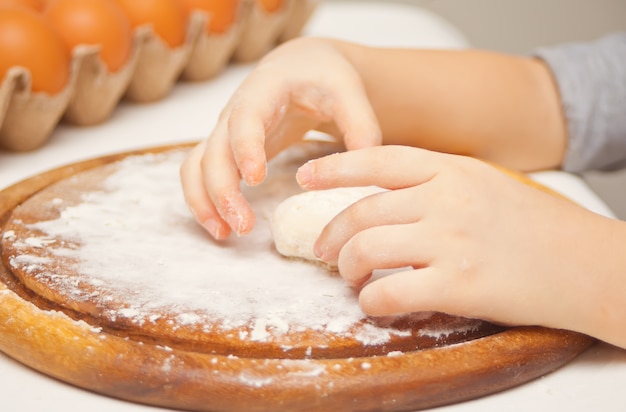 Piccolo bambino in cucina a casa preparare la pasta per la pizza o un altro cibo.