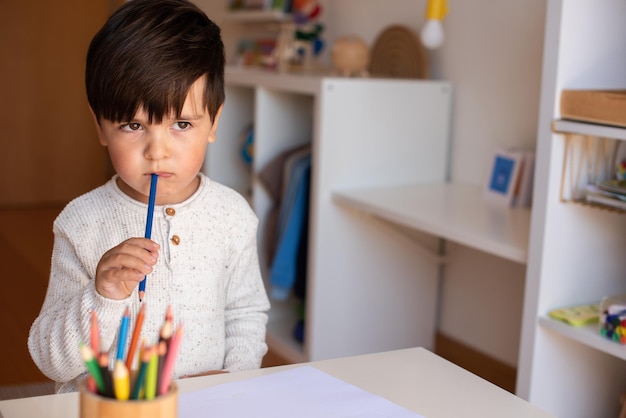 Piccolo bambino in età prescolare che disegna con le matite colorate. Istruzione a domicilio. Comunità di apprendimento. Scuola Montessori.