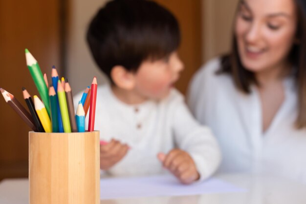 Piccolo bambino in età prescolare che disegna con matite colorate con madre o insegnante. Concentrati sulle matite. Istruzione a domicilio. Comunità di apprendimento. Scuola Montessori.