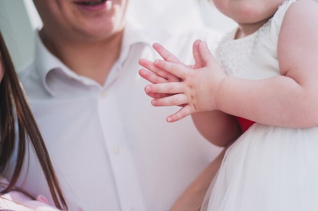 Piccolo bambino nelle mani d'applauso di un vestito bianco