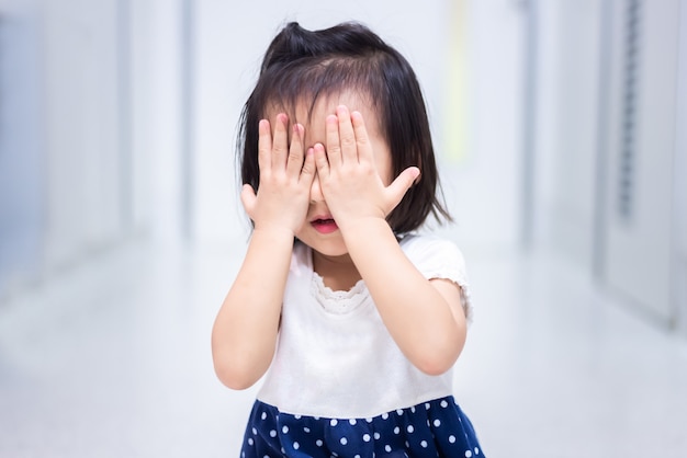 Piccolo bambino seduto su terra piangendo e coprirsi il viso con la mano