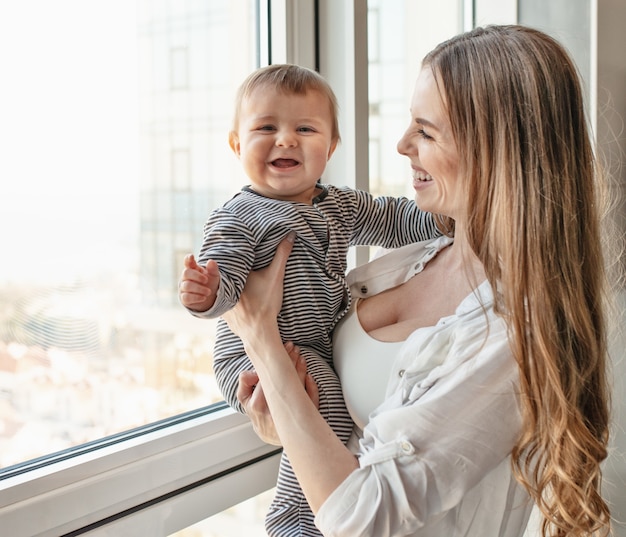 Piccolo bambino sorridente e felice con la mamma sul divano