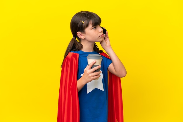 Piccolo bambino super eroe isolato su sfondo viola che tiene il caffè da portare via e un cellulare