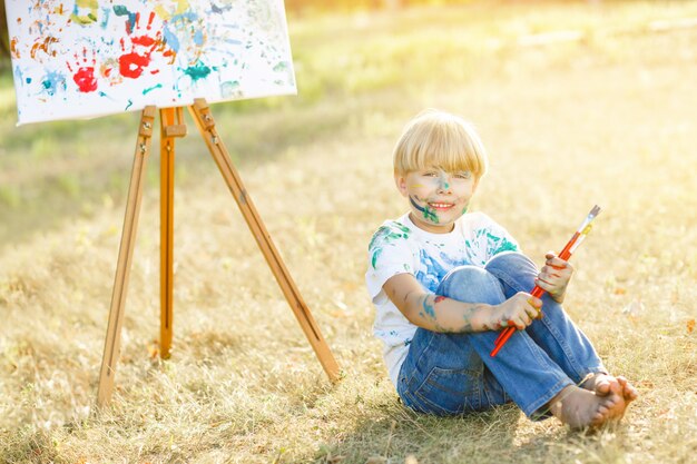 Piccolo bambino sveglio che dipinge all'aperto