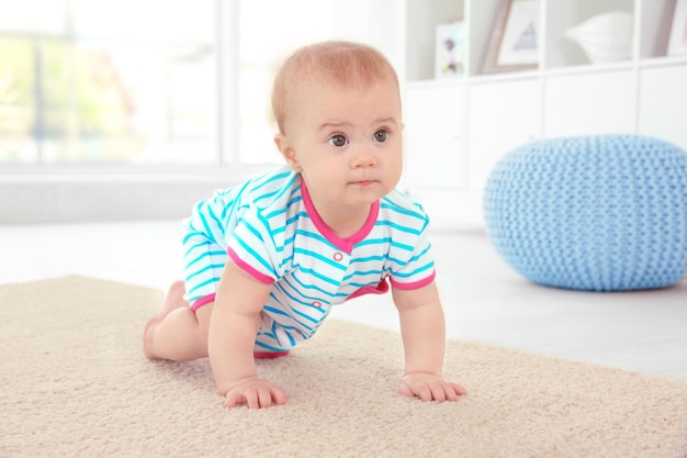 Piccolo bambino sveglio che striscia sul pavimento a casa