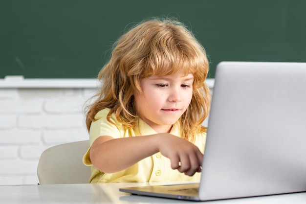 Piccolo bambino sveglio che usa il ragazzo del bambino del computer portatile che studia attraverso il piccolo sistema divertente di elearning online