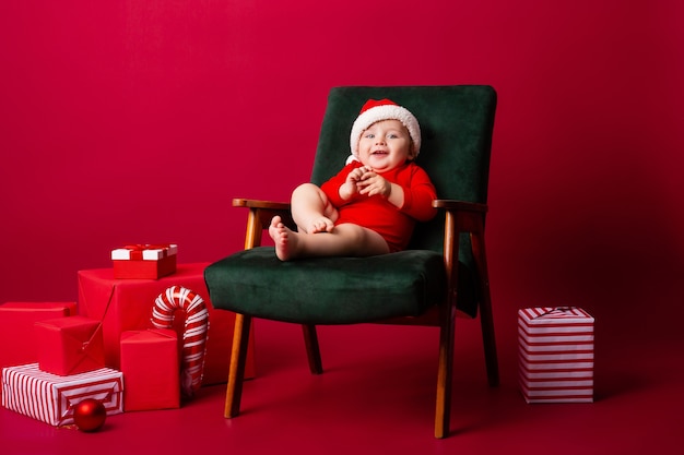 Piccolo bambino sveglio con un cappello della Santa su una sedia