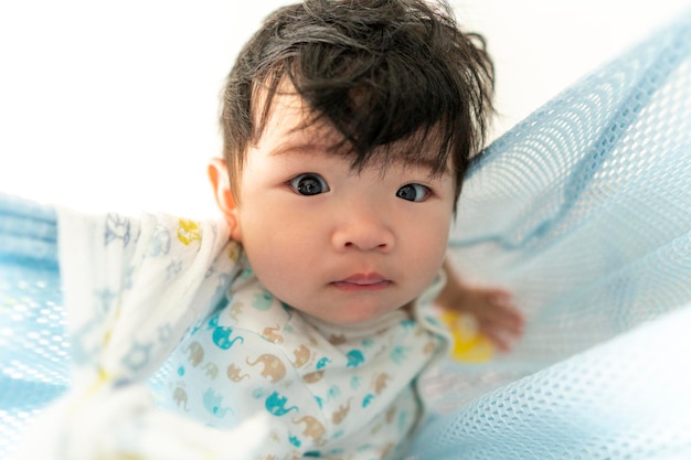 Piccolo bambino sveglio di sei mesi che esamina la macchina fotografica con espressione curiosa