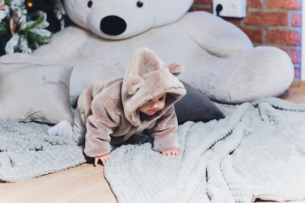 Piccolo bambino sveglio in un vestito con gli orsi nel pavimento.