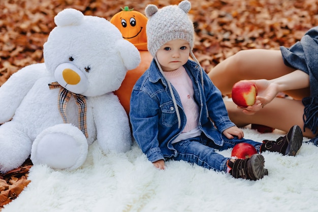 Piccolo bambino sveglio nel parco sulla foglia gialla con la zucca in autunno