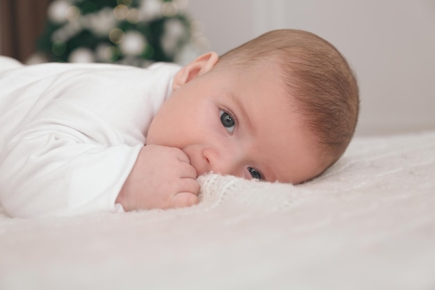 Piccolo bambino sveglio sulla coperta nella stanza con l'albero di Natale