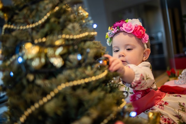 Piccolo bambino vicino all'albero di Natale prima della festa di capodanno