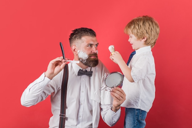 Piccolo barbiere. Concetto di barbiere. Salone per uomo. Look perfetto nel negozio di barbiere. Assistente per papà. Festa del papà. Rasatura barbuta nel negozio di barbiere. Cura della barba.