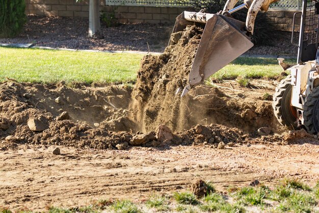 Piccolo bulldozer che scava nel cortile per l'installazione della piscina