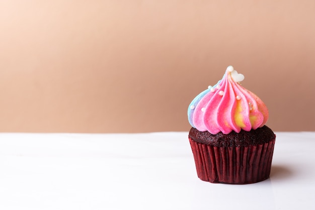 Piccolo cuore bianco sveglio sul bigné crema dell&#39;arcobaleno, concetto dolce del dessert