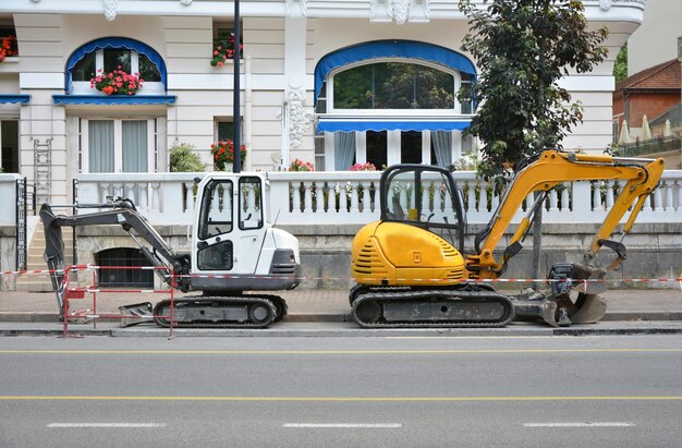 Piccolo escavatore bianco e giallo sulla strada in Francia Strada liscia