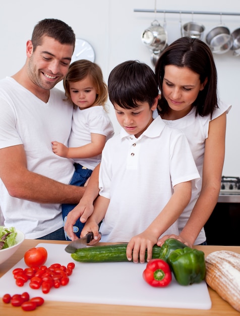 Piccolo figlio che prepara il cibo con la sua famiglia