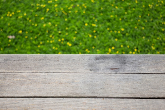 Piccolo fiore giallo su erba verde con fondo di legno