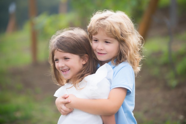 Piccolo fratello e sorella ragazzo e ragazza che giocano nel parco all'aperto Bambini felici che si divertono all'aperto Fratello e sorella che giocano nel parco primaverile Amicizia e gentilezza del bambino