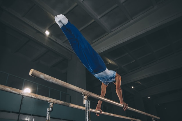 Piccolo ginnasta maschio che si allena in palestra, composto e attivo. Ragazzino in forma caucasica, atleta in abbigliamento sportivo che pratica esercizi per forza, equilibrio. Movimento, azione, movimento, concetto dinamico