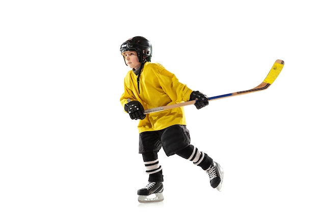 Piccolo giocatore di hockey con il bastone sul campo da ghiaccio e bianco