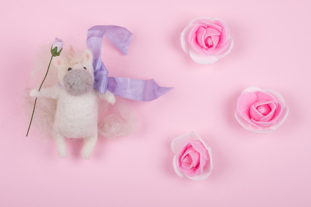 Piccolo giocattolo unicorno fatto di lana e boccioli di rosa fatti a mano