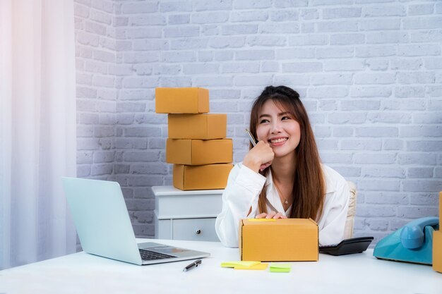 Piccolo imprenditore che lavora a casa con scatola di imballaggio sul posto di lavoro