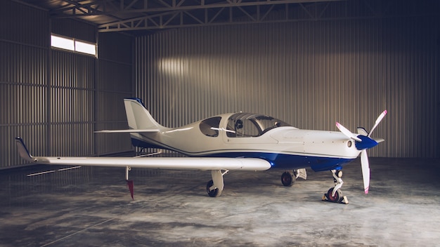 Piccolo jet privato bianco parcheggiato nell'hangar