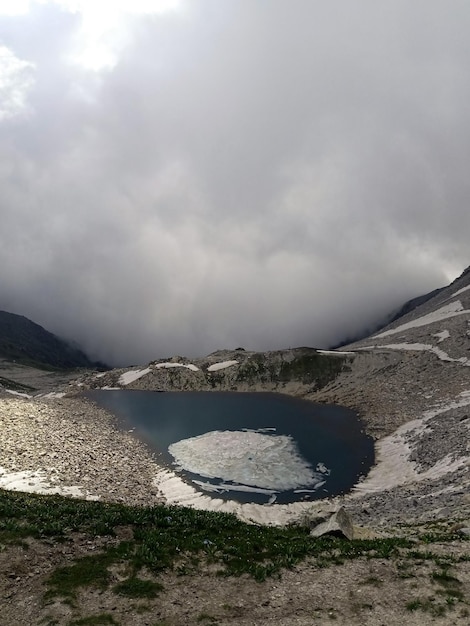 Piccolo lago ghiacciato sulla cima di una montagna rocciosa