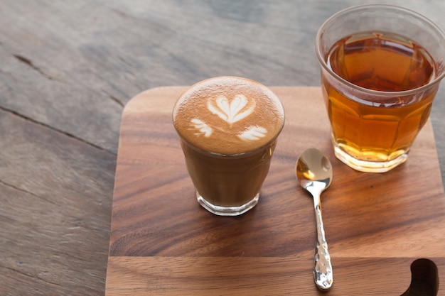 Piccolo Latte art in vetro piccolo con tè caldo sulla scrivania in legno