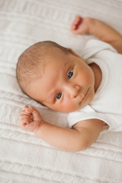 Piccolo neonato carino è sdraiato sul letto. Bambino.