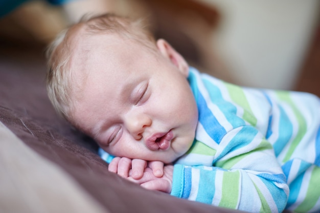 Piccolo neonato che dorme sul suo stomaco nel letto