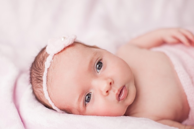 Piccolo neonato in un vestito rosa su uno sfondo rosa. Maternità.