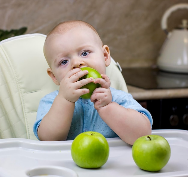 Piccolo neonato sveglio che mangia mela verde