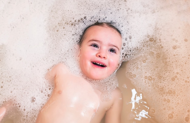 Piccolo nuoto felice del fronte della neonata nel bagno e nel sorriso