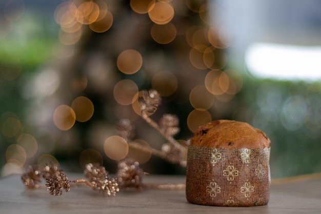 piccolo panettone panettone sul tavolo con sfondo sfocato di luci di Natale simbolo di Natale