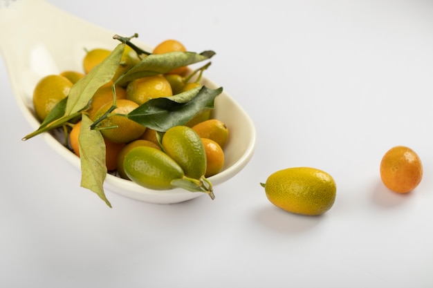 Piccolo piatto di frutta fresca kumquat sul tavolo bianco.