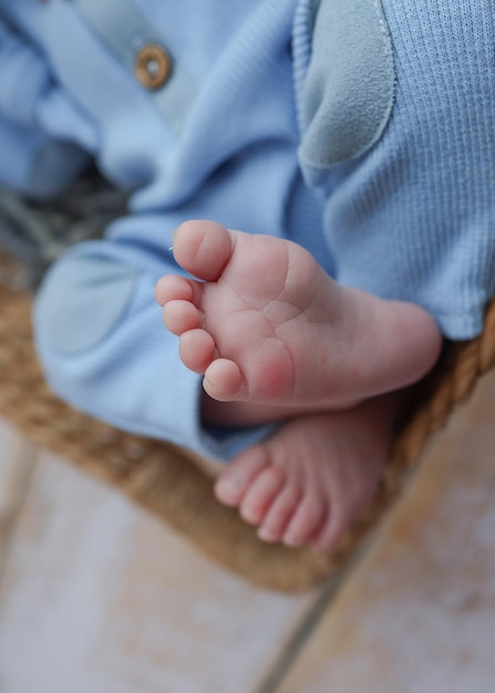 Piccolo piede di un neonato Gambe morbide di un neonato in tuta di lana blu su uno sfondo di legno naturale marrone Macro foto dei talloni e dei piedi di un neonato
