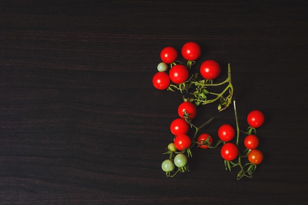 Piccolo pomodoro su fondo di legno nero