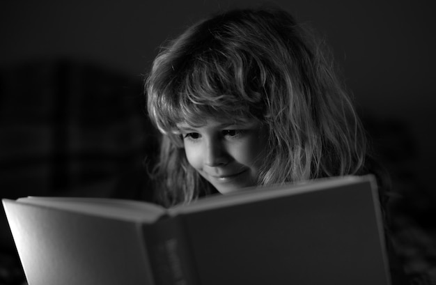 Piccolo ragazzo carino che legge un libro bambino con libro aperto lezione di scuola a casa concentrato piccolo ragazzo a letto