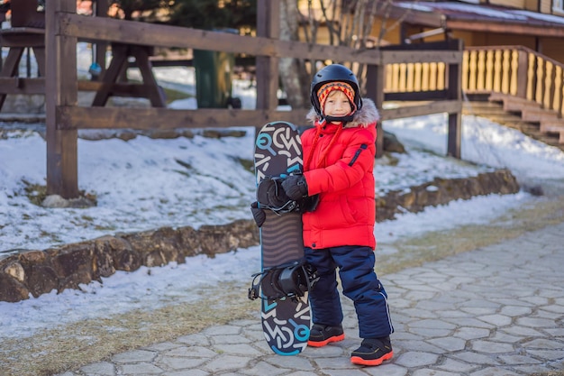 Piccolo ragazzo carino è pronto per lo snowboard Attività per bambini in inverno Sport invernali per bambini Stile di vita