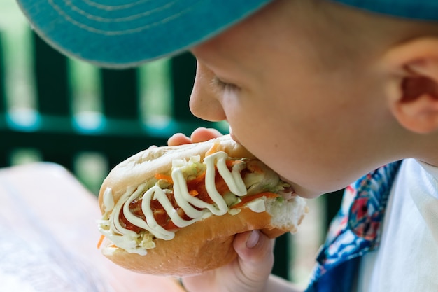 Piccolo ragazzo caucasico che mangia hamburger