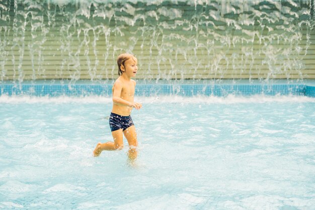 Piccolo ragazzo che si diverte a correre in piscina