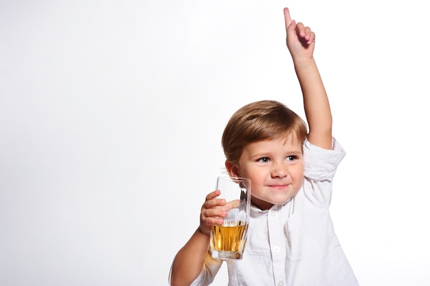 Piccolo ragazzo divertente che beve un succo fresco